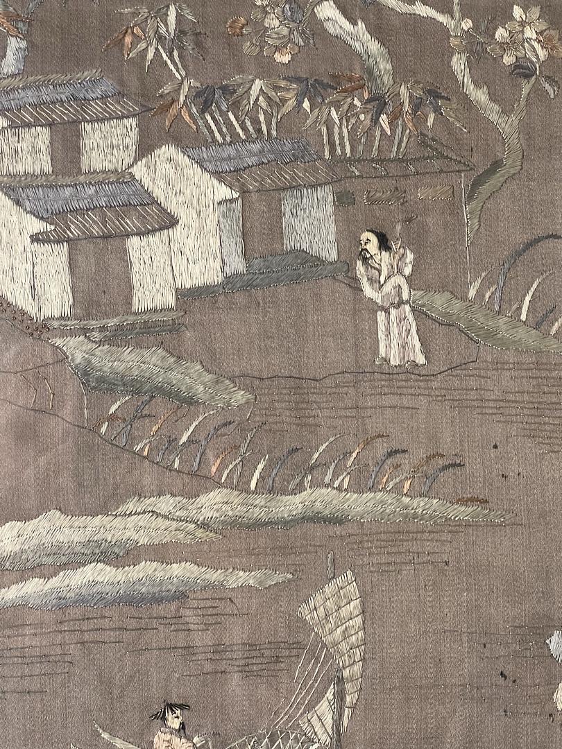 Antique Chinese Embroidered Panel on Silk c. Late 19th Century by Pearl City Antiques features traditional houses, a figure under trees, and another in a boat on textured brown silk—an exquisite decorative textile reminiscent of antique artistry.