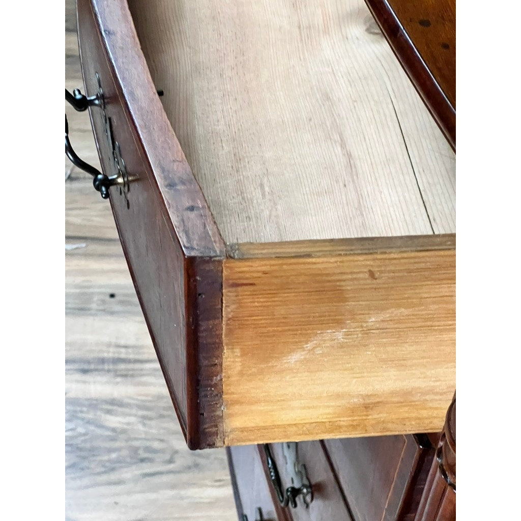 An open drawer with visible dovetail joints reveals its unfinished interior and edge, attached to an Antique Sheraton Mahogany Bowfront Chest c. Early 19th Century, placed on a wood-patterned floor. Brand: None/Unknown.