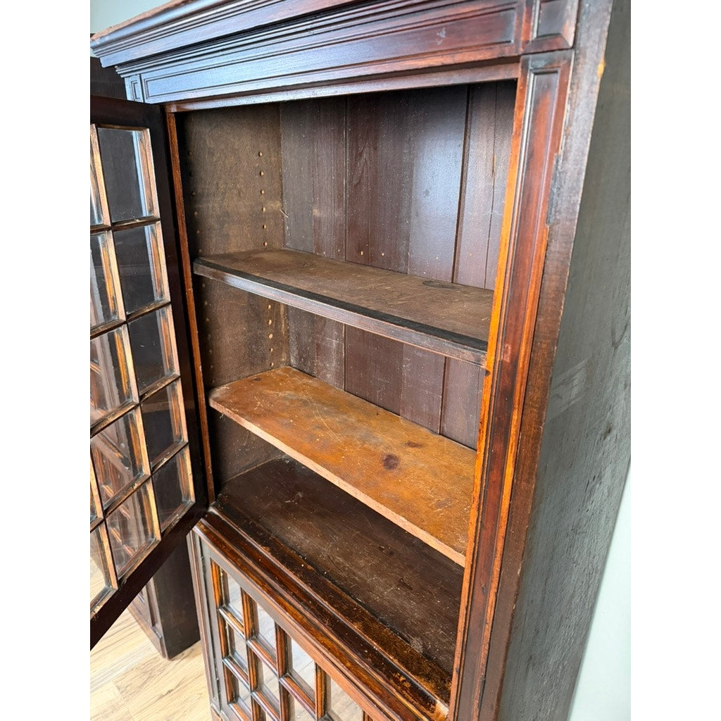 A Pair of Mid-19th Century New England Cherry Glazed Display Cupboards (c. 1840–1860) from Pearl City Antiques, featuring glass-paned doors and two shelves with visible wear and scratches on the cherrywood shelves and frame. The empty cupboards are shown standing on a wooden floor.