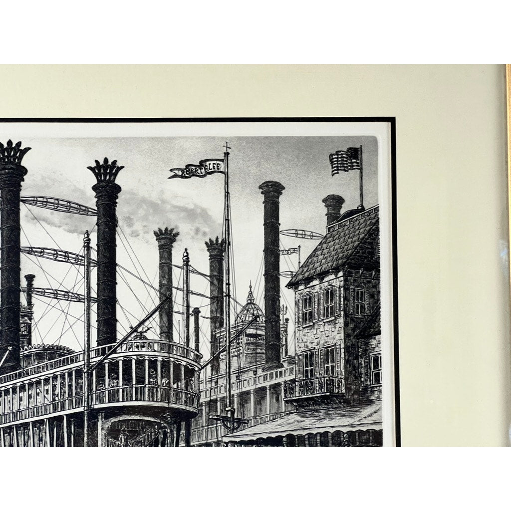 Framed Etching “Steamboat Robert E. Lee” by Alan Jay Gaines: A black and white framed etching features a steamboat with tall smokestacks and the flag “NATCHEZ,” docked near buildings with chimneys and an American flag on a rooftop. Brand: Unknown.