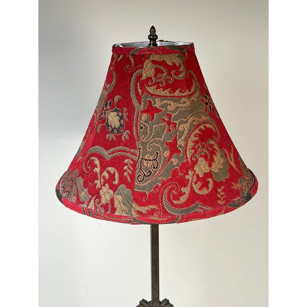 The Antique Art Deco Cast Iron Floor Lamp by Rembrandt features a dark cast iron base and is crowned with a red and gold brocade lampshade adorned with intricate floral and dragon patterns, standing elegantly against a simple background.