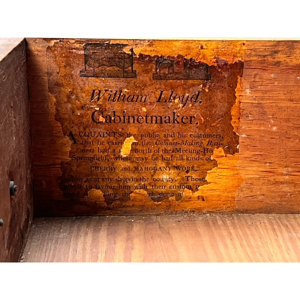 A worn label inside this rare William Lloyd Springfield, Massachusetts Federal cherry chest of drawers, circa 1800, bears the cabinetmaker’s name and faded early American furniture and carpentry advertisements, now partially obscured and peeling with age.