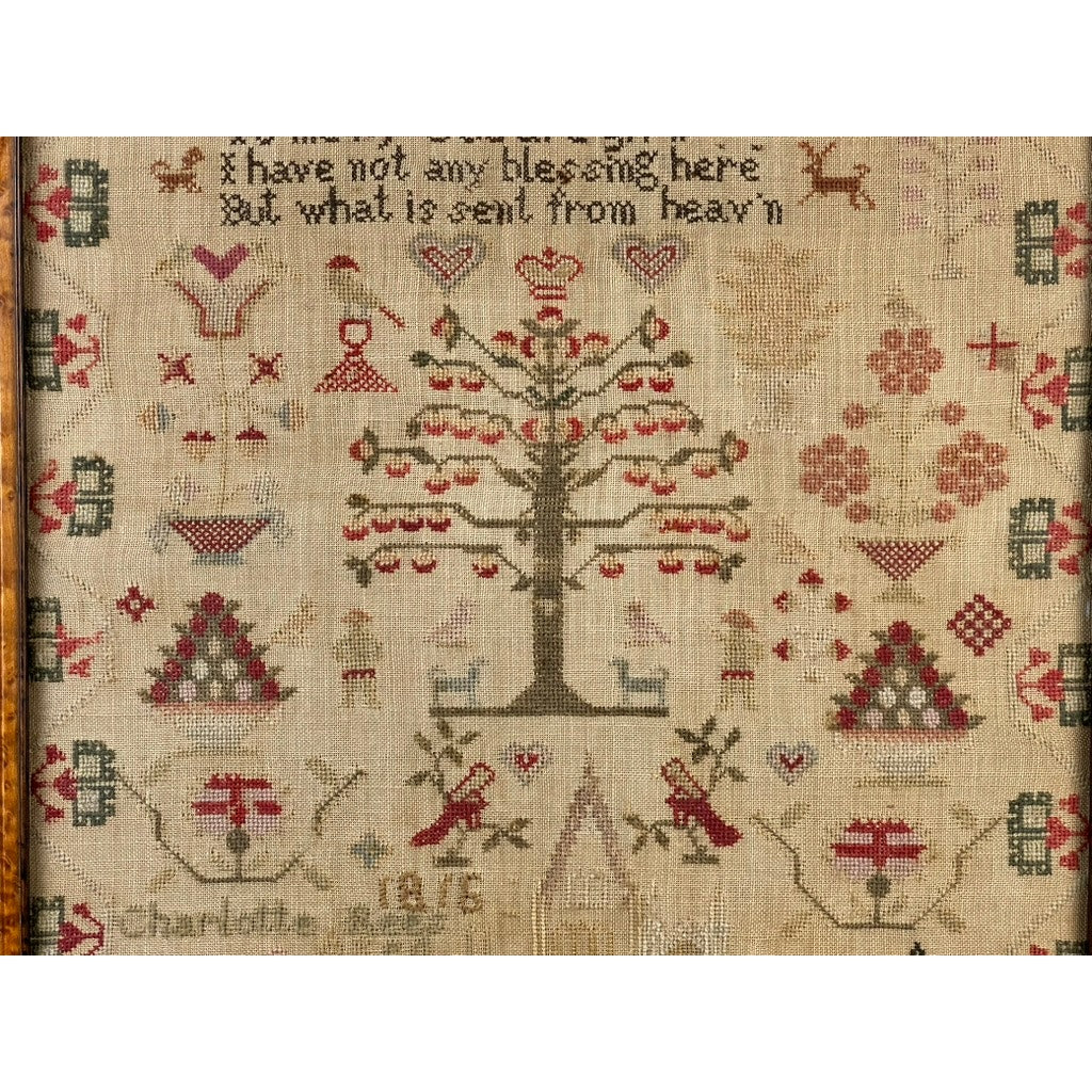 An exceptional English Regency schoolgirl needlework sampler by Charlotte Rees, age 11, dated 1816. This vintage antique piece showcases a central tree surrounded by geometric patterns, hearts, birds, and figures. The top is inscribed with the phrase: “I have not any blessing here but what is sent from heav’n,” while Charlotte’s name and the year 1816 are stitched below in true Regency-era style.