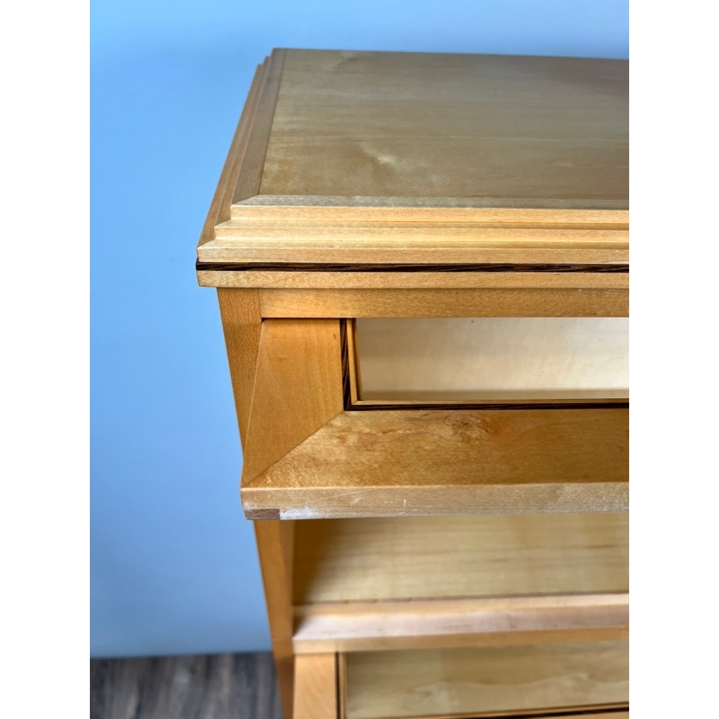 A close-up shows the top corner of a light wooden dresser with open drawers, set beside a Vintage Bench Made Maple with Wenge Inlay Three Stack Barrister Bookcase, against a blue wall and wood-patterned floor for classic charm.