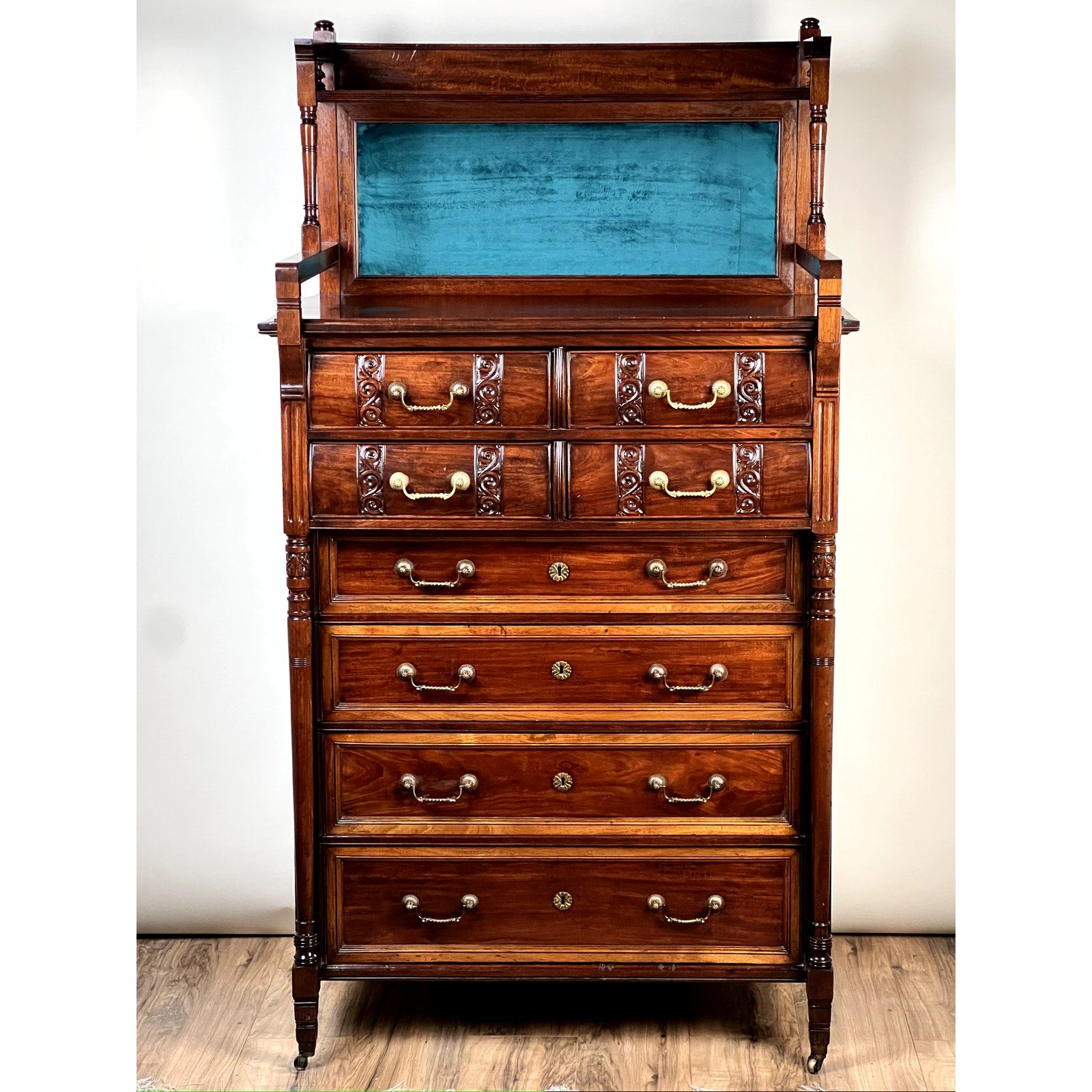 Antique Victorian Aesthetic Movement mahogany four over four gentlemen’s chest c. 1880 with ornate carvings, brass handles, blue velvet-backed display shelf, and decorative legs on casters—a fine period piece.