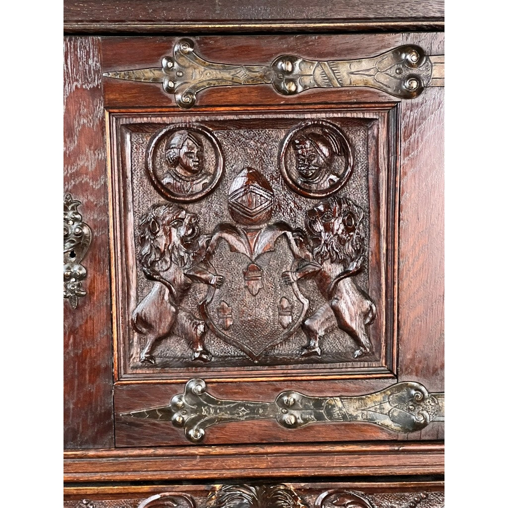 Antique 19th-century French Breton-style carved oak cabinet featuring deeply carved knights, ornate panel accents, and decorative metal hinges at the corners—an exquisite antique storage piece.