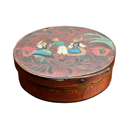 Antique German polychrome-painted bentwood "Spanschachtel" ribbon box, late 18th century, featuring a round reddish-brown shape, decorative trim, and a colorful lid with European folk art of three dancers amid florals and swirls.