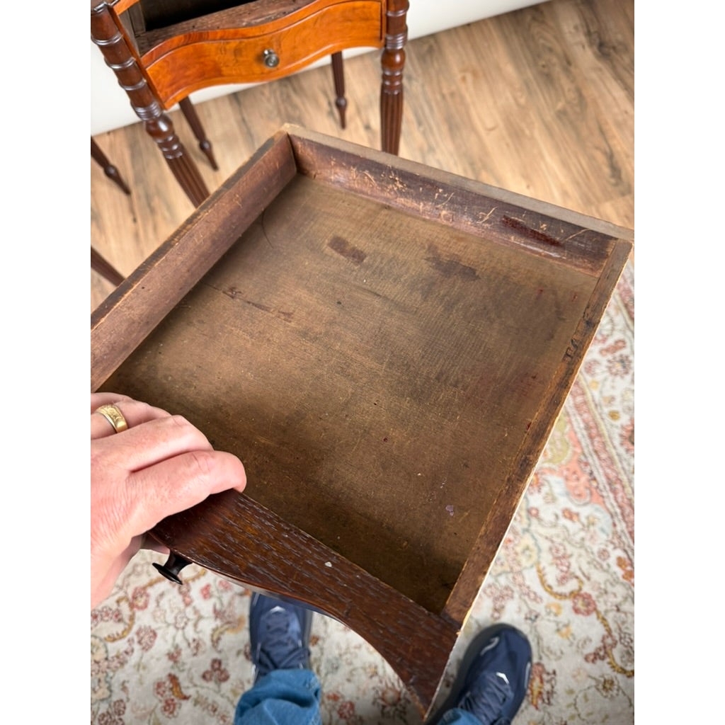 A person holds an open wooden drawer from an antique Pair of American Classical Revival Mahogany Two-Drawer Work Tables, circa 1880–1910.