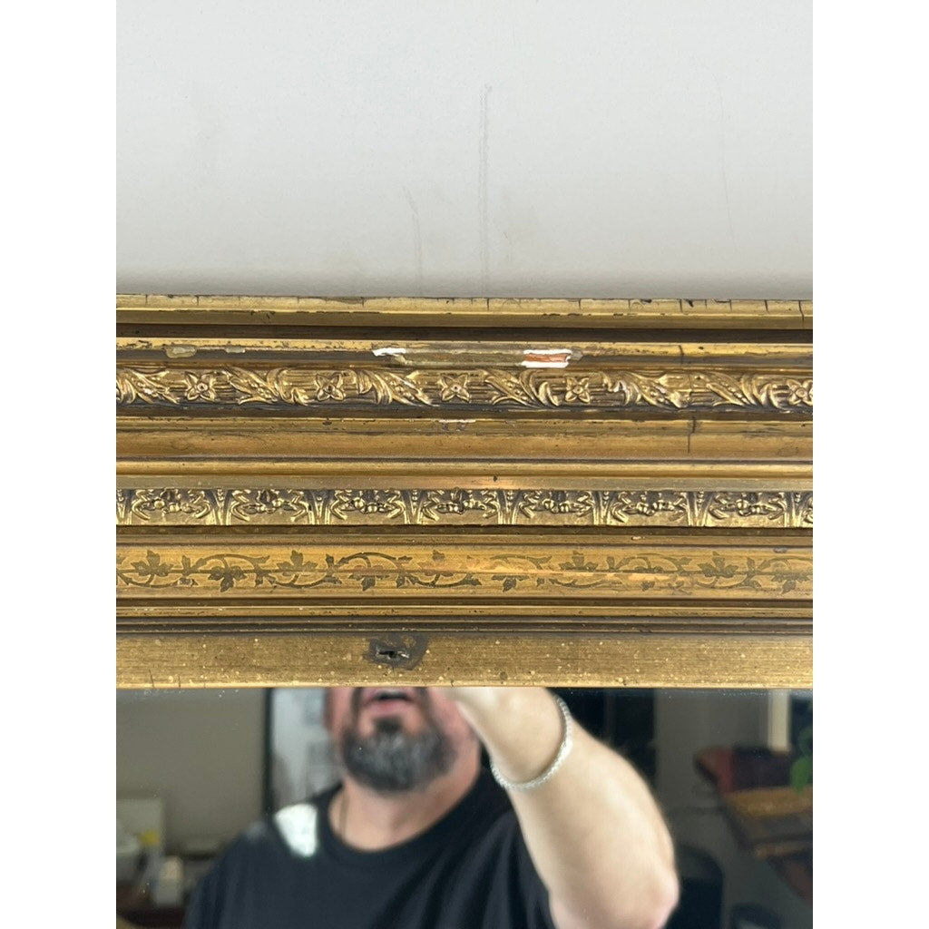 A man stands before a Fine Antique 19th Century Gilt Wood Mirror (39 x 34); the focus is on the detailed floral frame, with only his lower face and upper body reflected. Brand: Unknown.