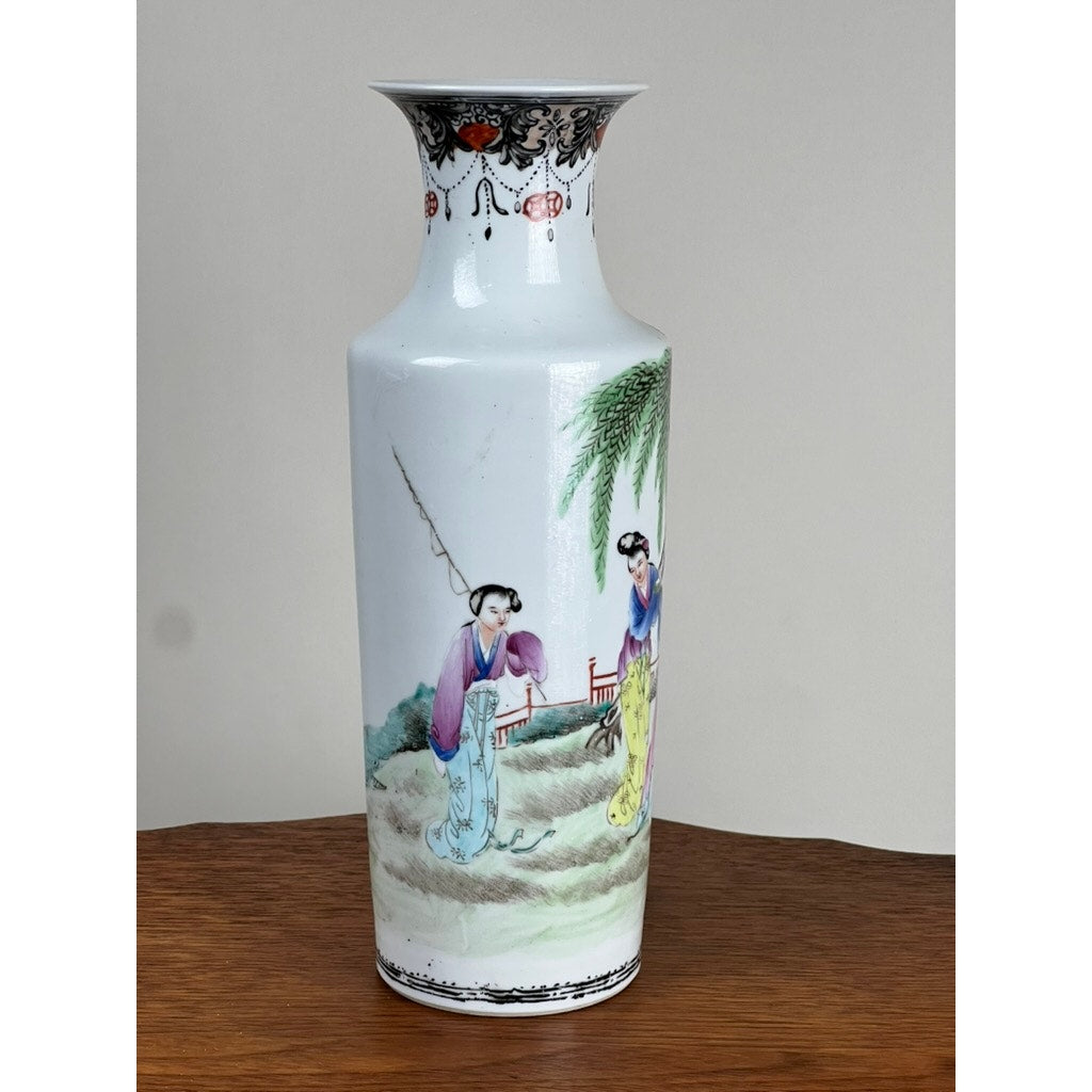 Antique Qing Dynasty Famille Rose 12” Vase with Qianlong Mark, white porcelain with a flared rim, features colorful painted figures of two women in traditional dress outdoors amid trees and a fence.