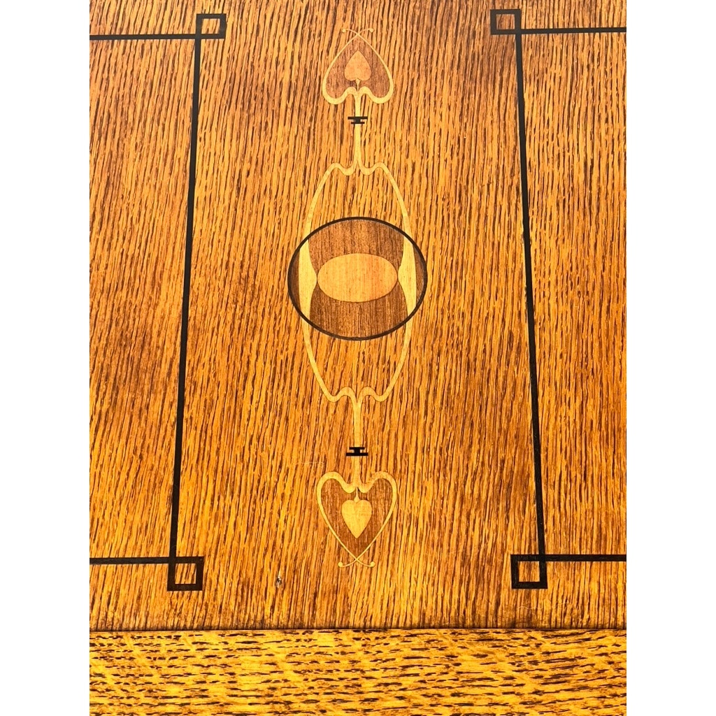 A close-up of the Stickley Vintage Harvey Ellis Millennium Edition Oak Blanket Chest showcases decorative oval and heart inlays, black framing lines, and corner accents—signature Arts & Crafts details. The rich oak grain adds warmth and texture.