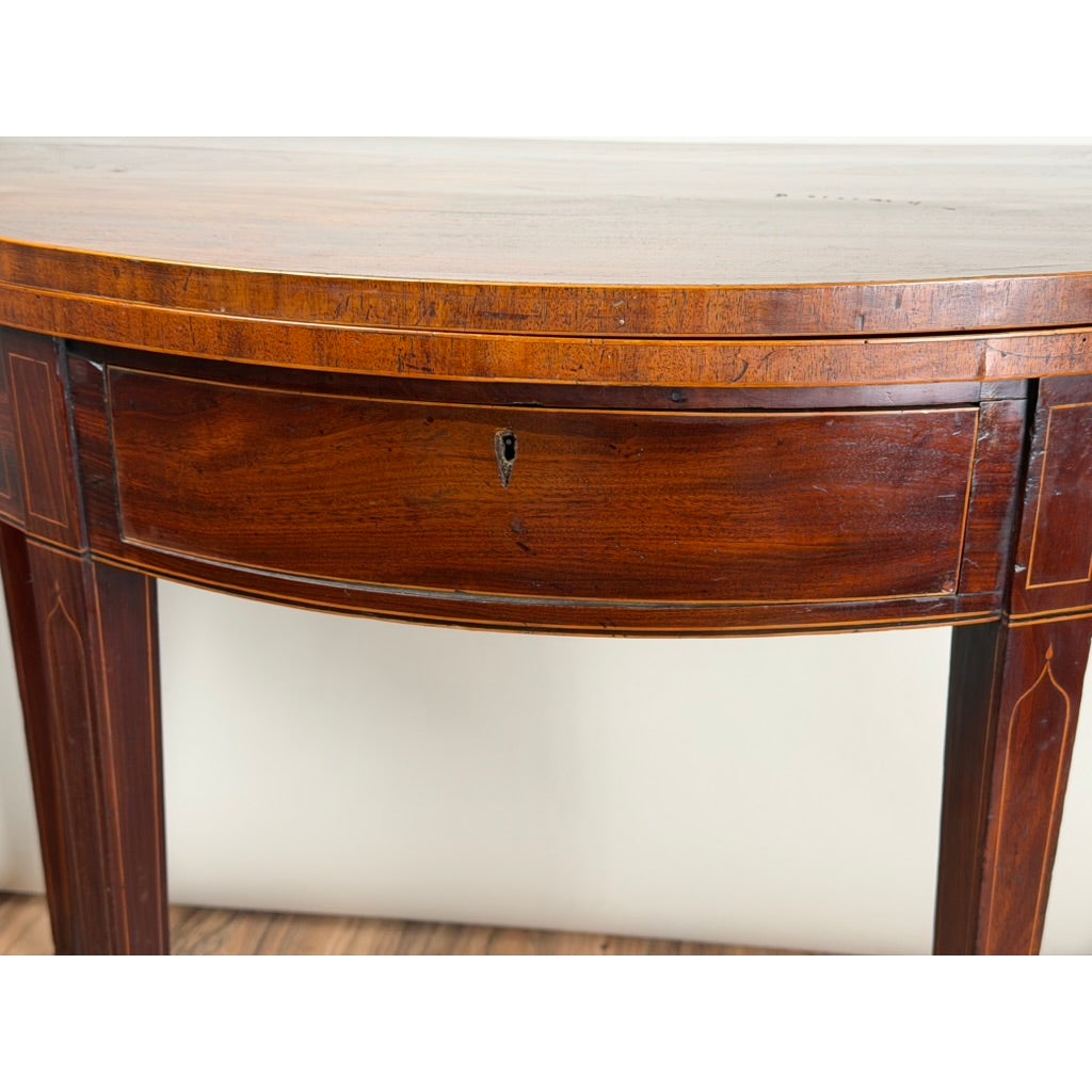 An English George III Mahogany and Satinwood-Inlaid Demilune Games Table, circa 1790–1810, featuring light wood inlay and a central keyhole on the apron.