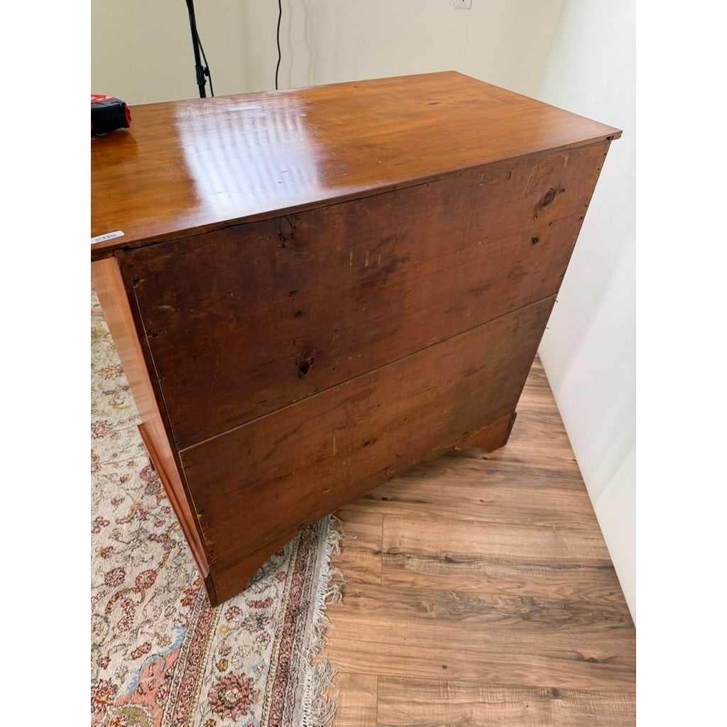 Rear view of a Pennsylvania Federal Cherry Four-Drawer Chest with Satinwood String Inlay, showing its cherry wood grain and bracket feet.