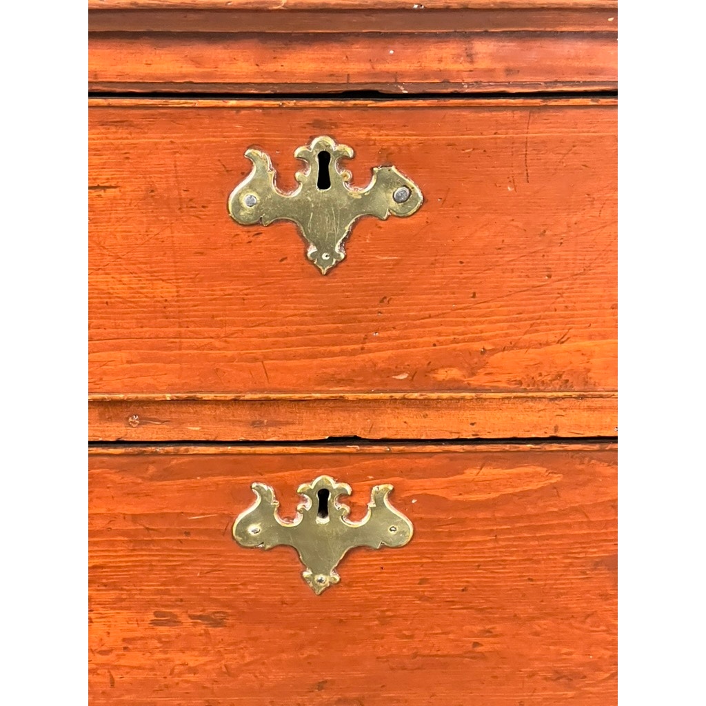 Close-up of two antique pine drawers from a late 18th-century Chippendale graduated four-drawer chest, attributed to a Northampton, MA maker, showing ornate brass keyhole plates and aged reddish-orange wood finish.