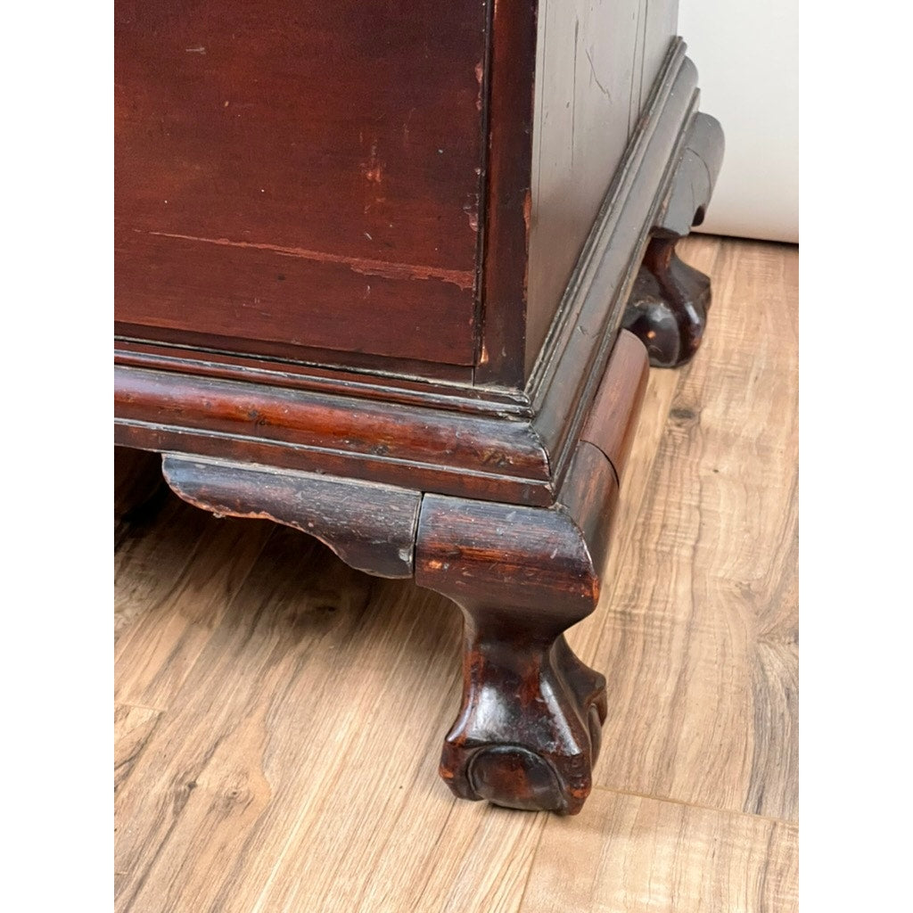 The photo showcases the carved wooden leg and lower corner of an 18th Century New England Chippendale Cherry Slant Front Desk (circa 1770–1790) on a light wood floor, emphasizing its detailed craftsmanship and worn finish that reflect the classic style of antique New England furniture.