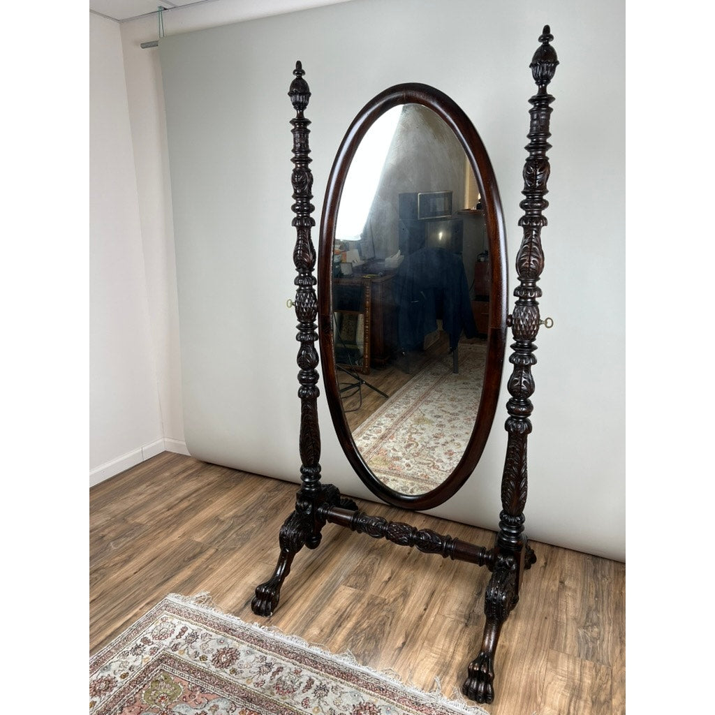 An Impressive Antique American Empire Acanthus and Barbola Rose Carved Cheval Mirror c. 1840 stands on a patterned rug in a wood-floored, neutral-walled room, reflecting a desk and studio lighting in the background. Brand: Unknown.