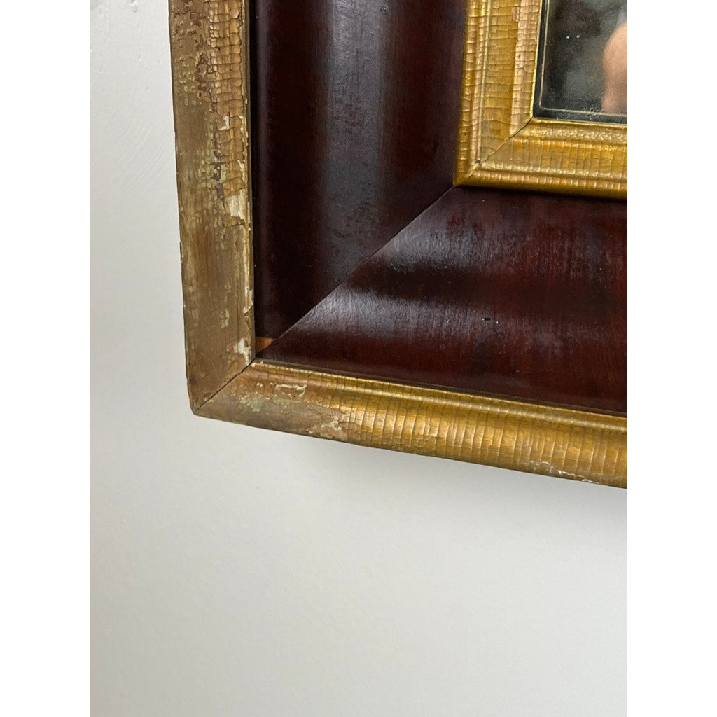 Close-up of the corner of an Antique American Empire Parcel Gilt Flame Mahogany Ogee Wall Mirror (mid-19th century); gold trim is chipped and worn, revealing underlying material. The frame rests against a white wall. Brand: Unknown.