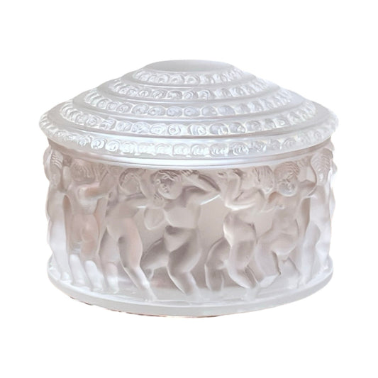 The Vintage Lalique Crystal Enfants Box by Lalique is a frosted glass round box with a domed lid, adorned with dancing nude cherubs and intricate designs, inspired by classic French art glass.