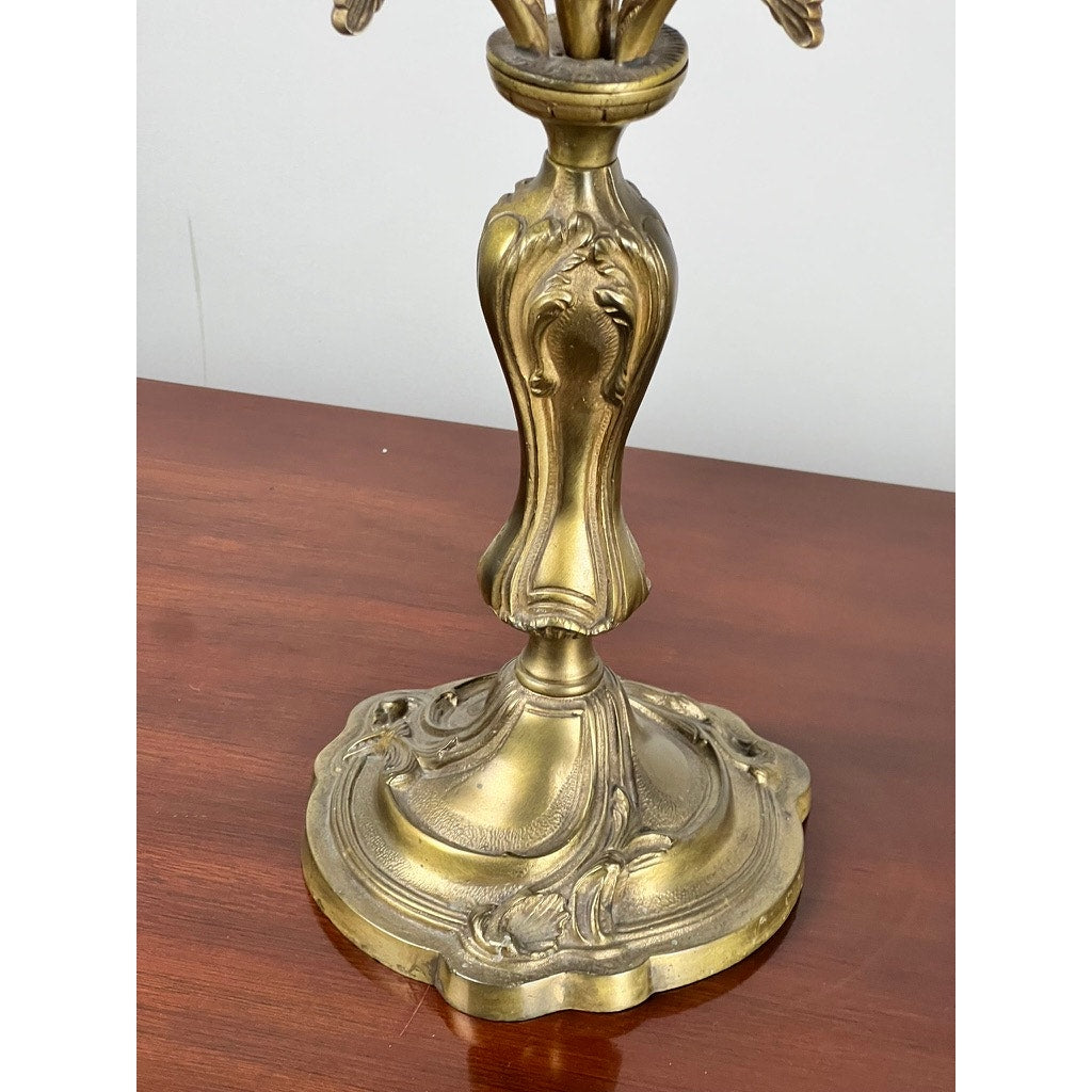 A close-up of a Vintage Brass Louis XV Style Four Light Candelabra base with intricate decorative patterns, resting on a polished wooden surface. Brand: None/Unknown.