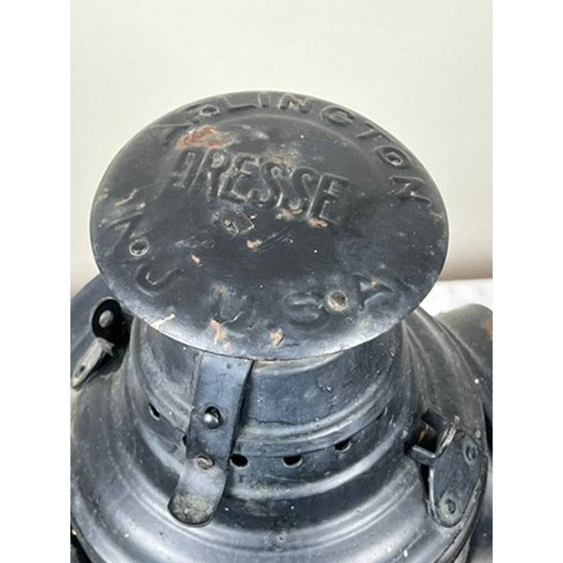 Close-up of a vintage Dressel Arlington NJ lantern, an Antique Illinois Central Railroad Signal Lantern. The black metal is worn with scratches and embossed “ARLINGTON DRESSE NO. 4 USA” text on top, echoing classic railroad history.