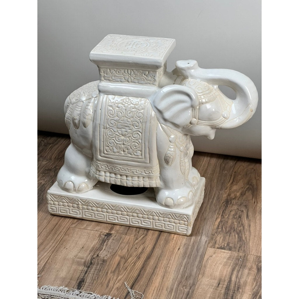 A vintage pair of white glazed Hollywood Regency style elephant garden seats, featuring intricate detailing and flat rectangular tops, adds elegant flair to any space. Brand: Unknown.