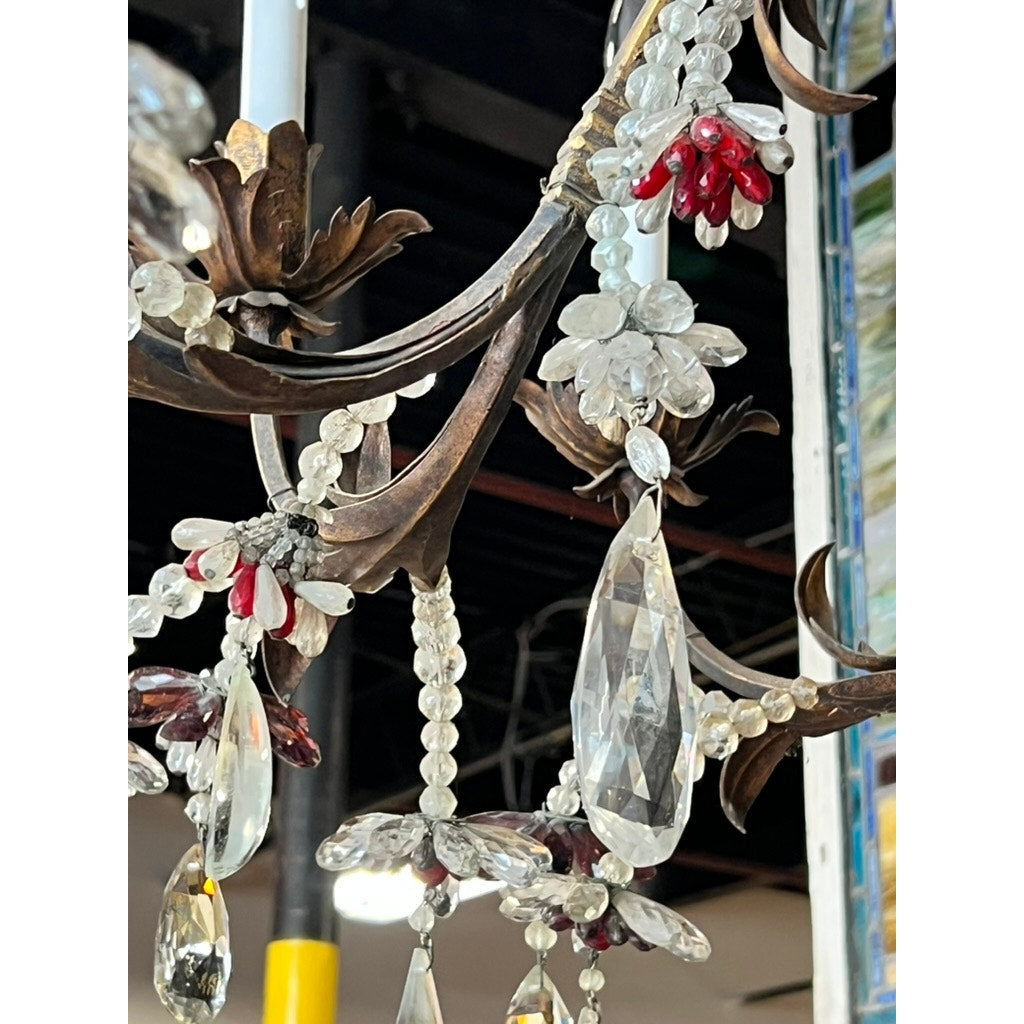 A close-up of an Antique Late 19th Century French Rococo Tole Amethyst and Crystal Ten Light Chandelier with clear crystal beads, amethyst accents, teardrop pendants, and ornate bronze floral arms shimmering beneath exposed ceiling beams.