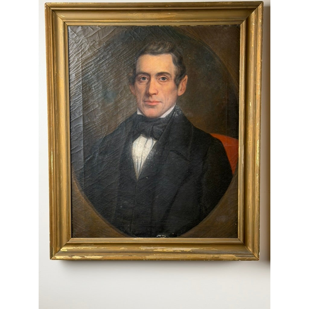Oil portrait of a gentleman from a Pair of American School Oil Portraits of a Gentleman and Lady, c. 1840–1860, featuring a man in a black coat and cravat within an oval frame inside an antique rectangular gold frame.