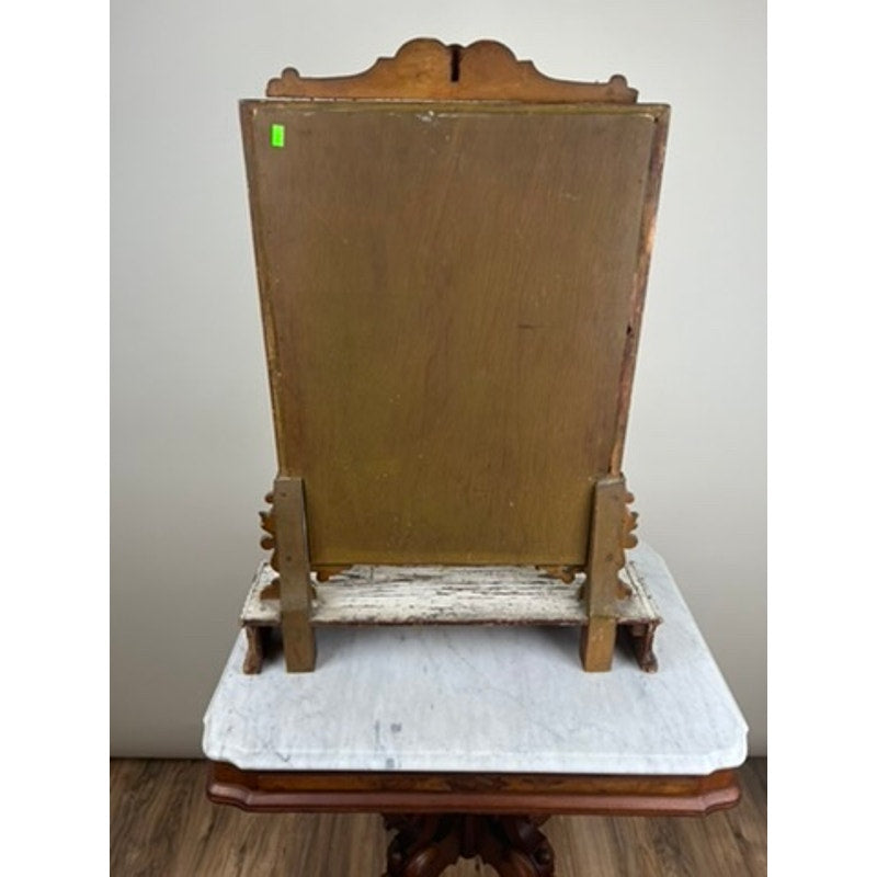 An Antique French Empire Gilt Wood Vanity or Table Mirror (c. Mid 19th Century) with a rectangular frame is shown from the back, resting on a marble-topped wooden table with ornate legs. The mirror stand displays an aged patina.