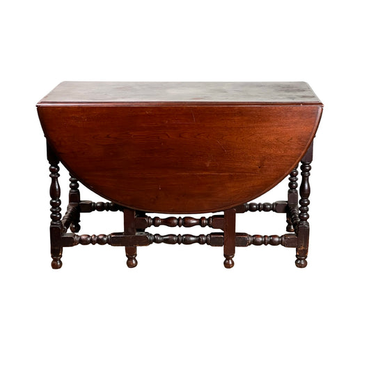 An Antique English William & Mary walnut one-drawer gateleg dining table from the early 18th century, featuring turned legs, stretchers, and drop leaves—one extended as a semicircle, exemplifying early English furniture style.