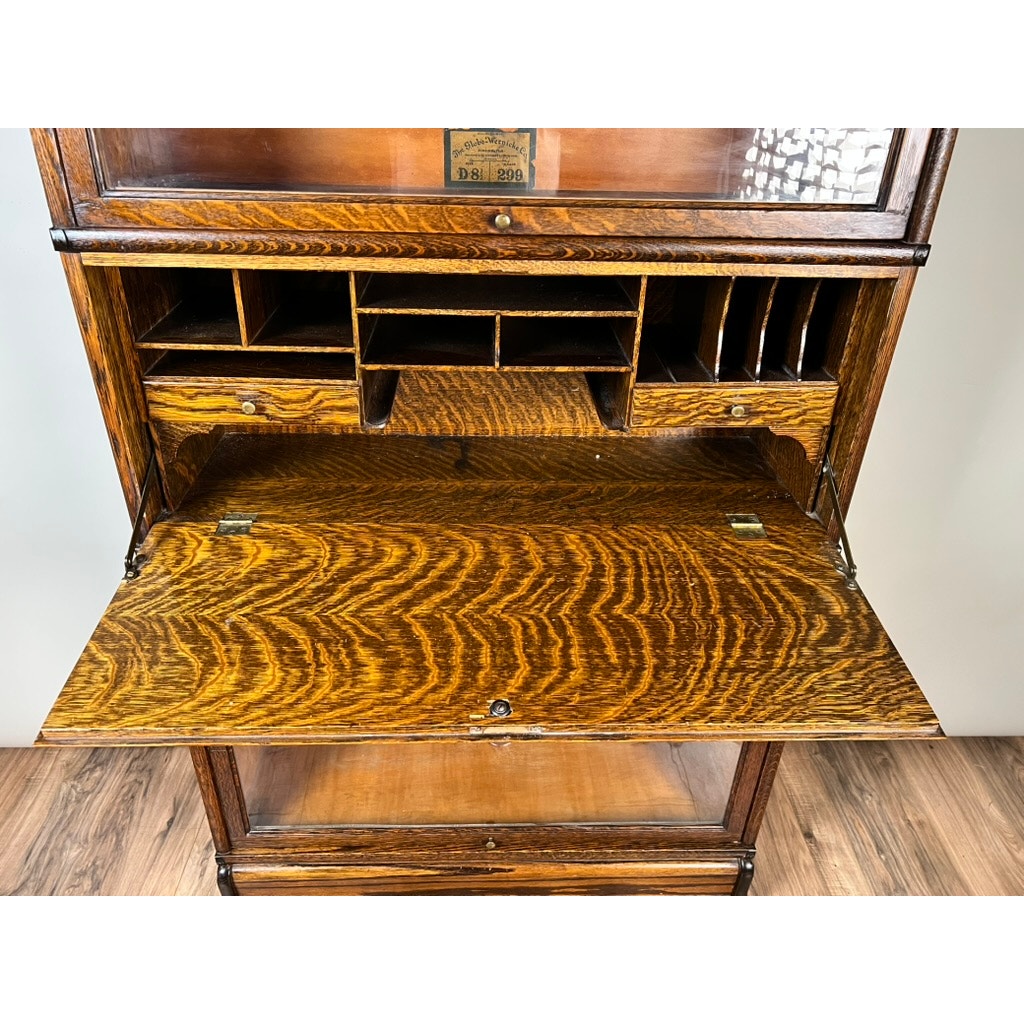 The Antique Globe-Wernicke Quarter Sawn Oak 6-Stack Barrister Bookcase Secretary Desk by Globe Wernicke (c. 1905–1915) features an open drop-down writing surface, multiple interior cubby compartments, and a striking quarter-sawn oak grain pattern, displayed on a wooden floor.