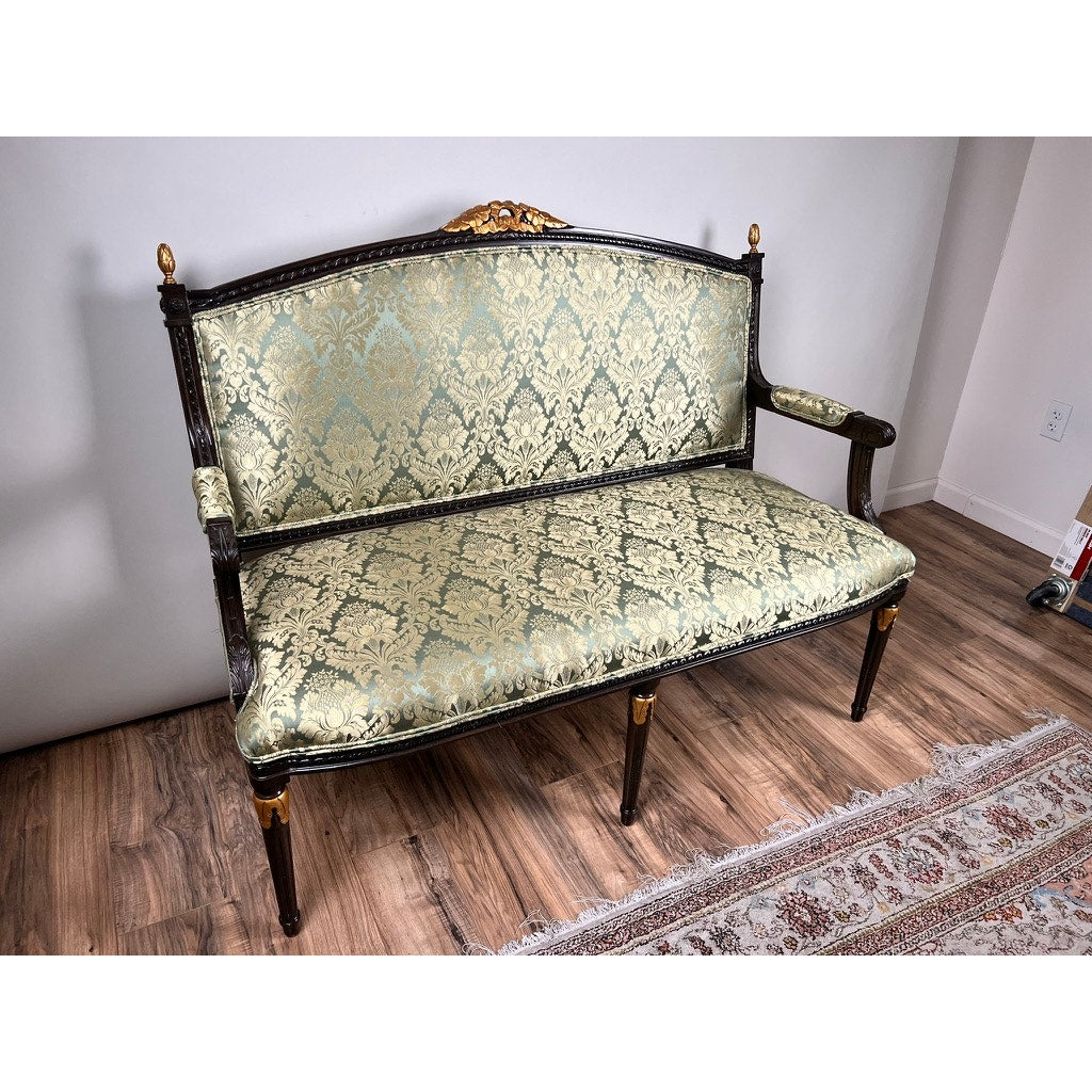 A Vintage Louis XVI Style Settee in green damask upholstery sits on a wood floor beside a patterned rug, set against light-colored walls. Brand: None and/or Unknown.