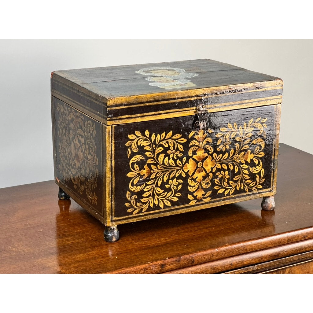 An Antique New England Folk Art Painted Portrait Document Box, c. 1840–1860, featuring a mother and child design, rests atop a polished wooden surface against a plain background. Brand: Unknown.