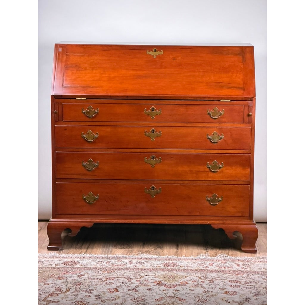 A Chippendale Cherry Slant-Front Desk with Ogee Bracket Feet, possibly Connecticut River Valley, circa 1770–1790, featuring four cherry wood drawers with brass pulls and ogee bracket feet, characteristic of New England antique furniture.