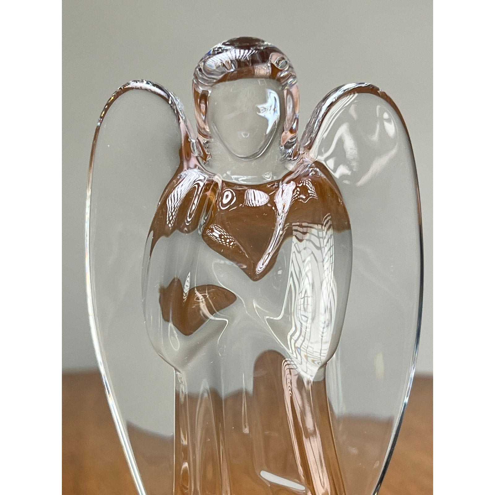 The Vintage Baccarat Crystal Angel by Baccarat is a clear crystal figurine with folded arms and etched details, displayed on a wooden surface against a plain background.