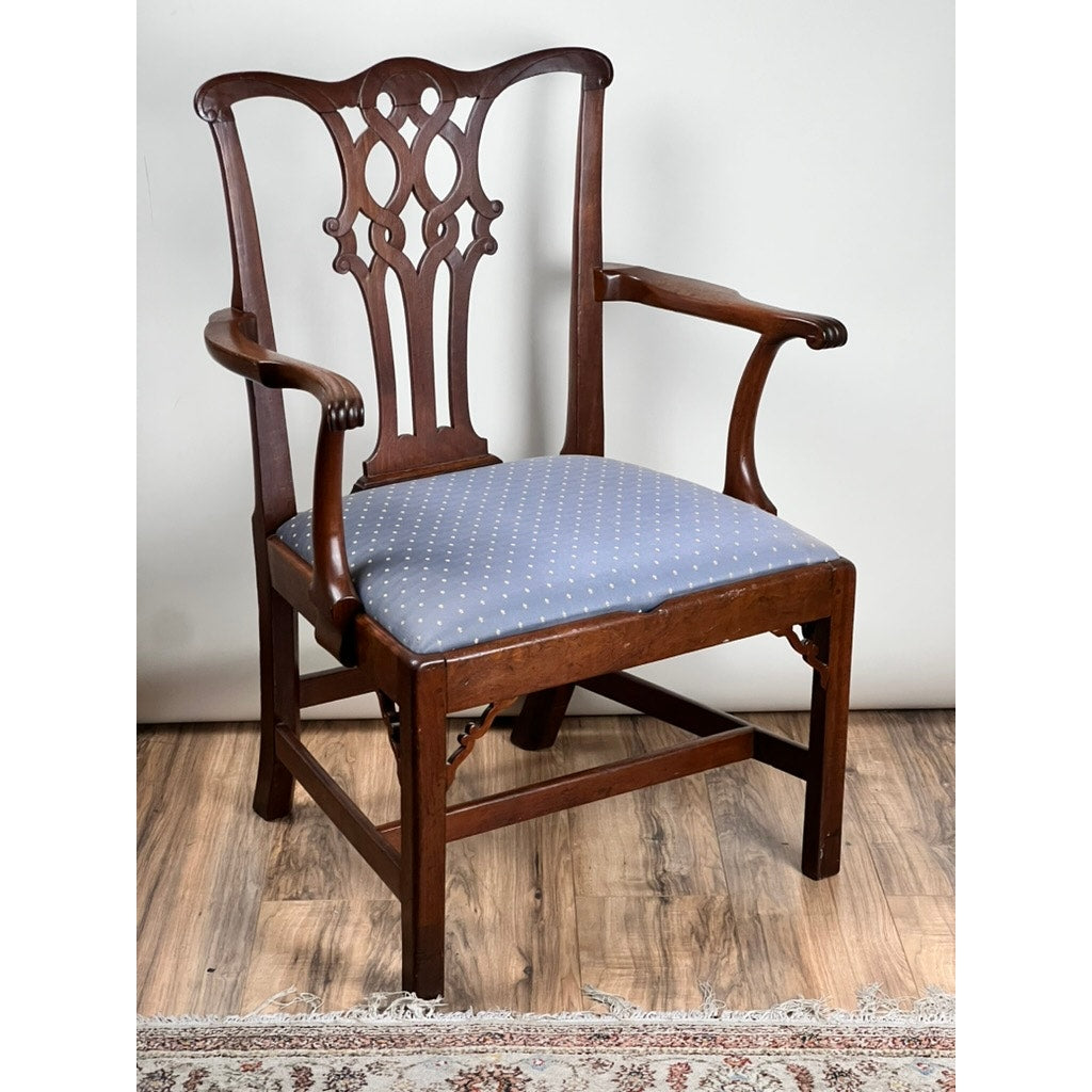 An Antique Chippendale Walnut Open Arm Chair c. Late 18th Century features an intricately carved backrest, curved armrests, and a seat upholstered in light blue fabric with small white dots, set on a wood floor beside a rug. Brand: None/Unknown.