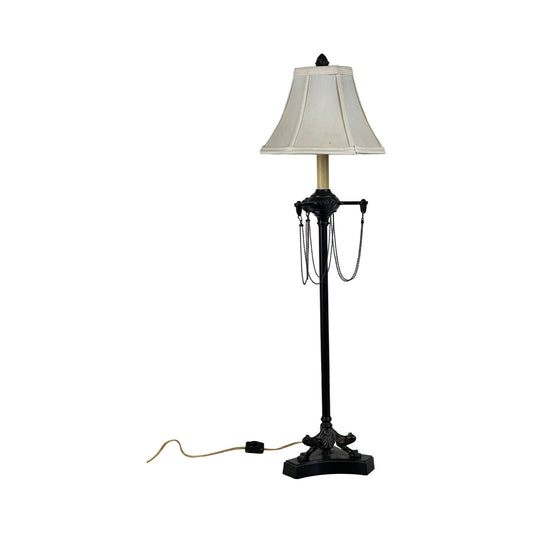 The Vintage French Empire Revival Table Lamp in an oiled bronze finish features ornate detailing, a beige tapered lampshade, and a visible power cord with switch, styled against a plain white background. Brand is unknown.