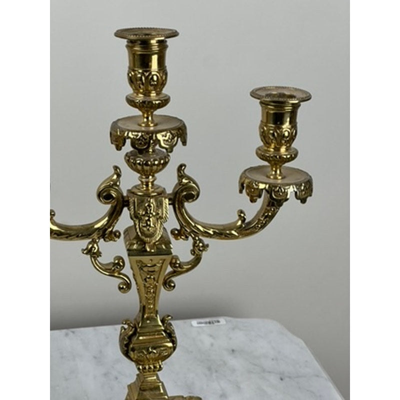 A close-up of an Antique Pair Late 19th Century Brass Three Light Candelabra with ornate scrollwork, shown on a white marble surface—ideal for adding elegant Victorian charm to your decor. Brand: Unknown.