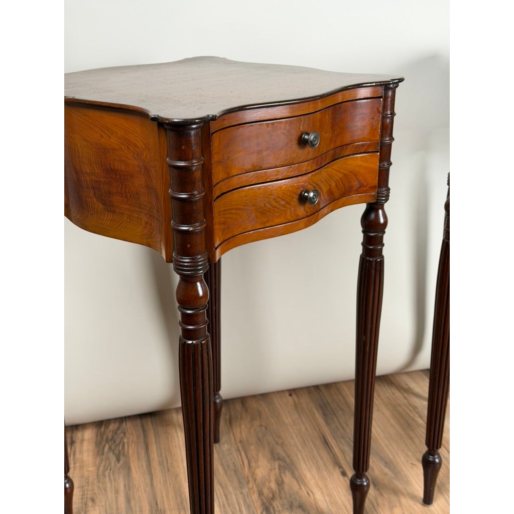 A pair of American Classical Revival Mahogany Two-Drawer Work Tables, circa 1880–1910, featuring wooden two-drawer construction with a serpentine front and fluted legs.