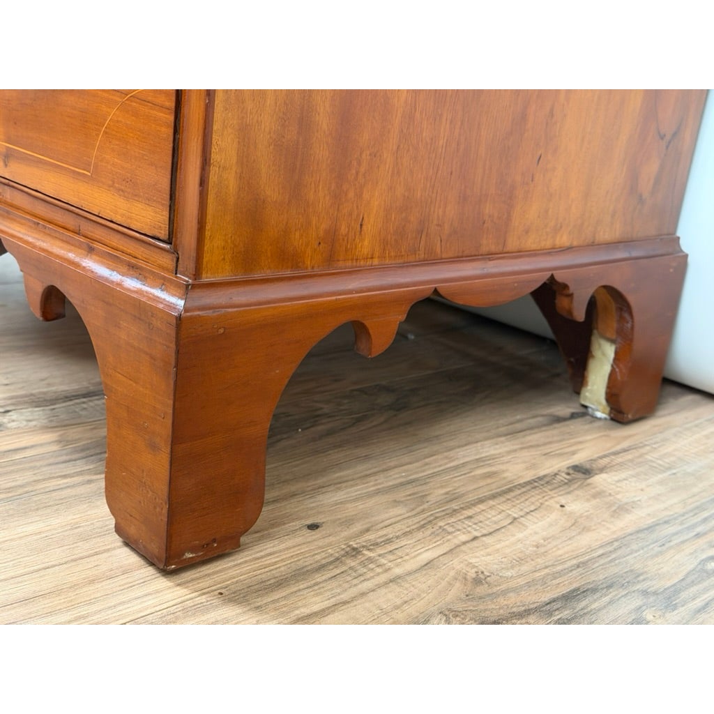 Close-up of the scalloped apron and bracket feet of a Pennsylvania Federal Cherry Four-Drawer Chest with Satinwood String Inlay, circa 1800–1820.