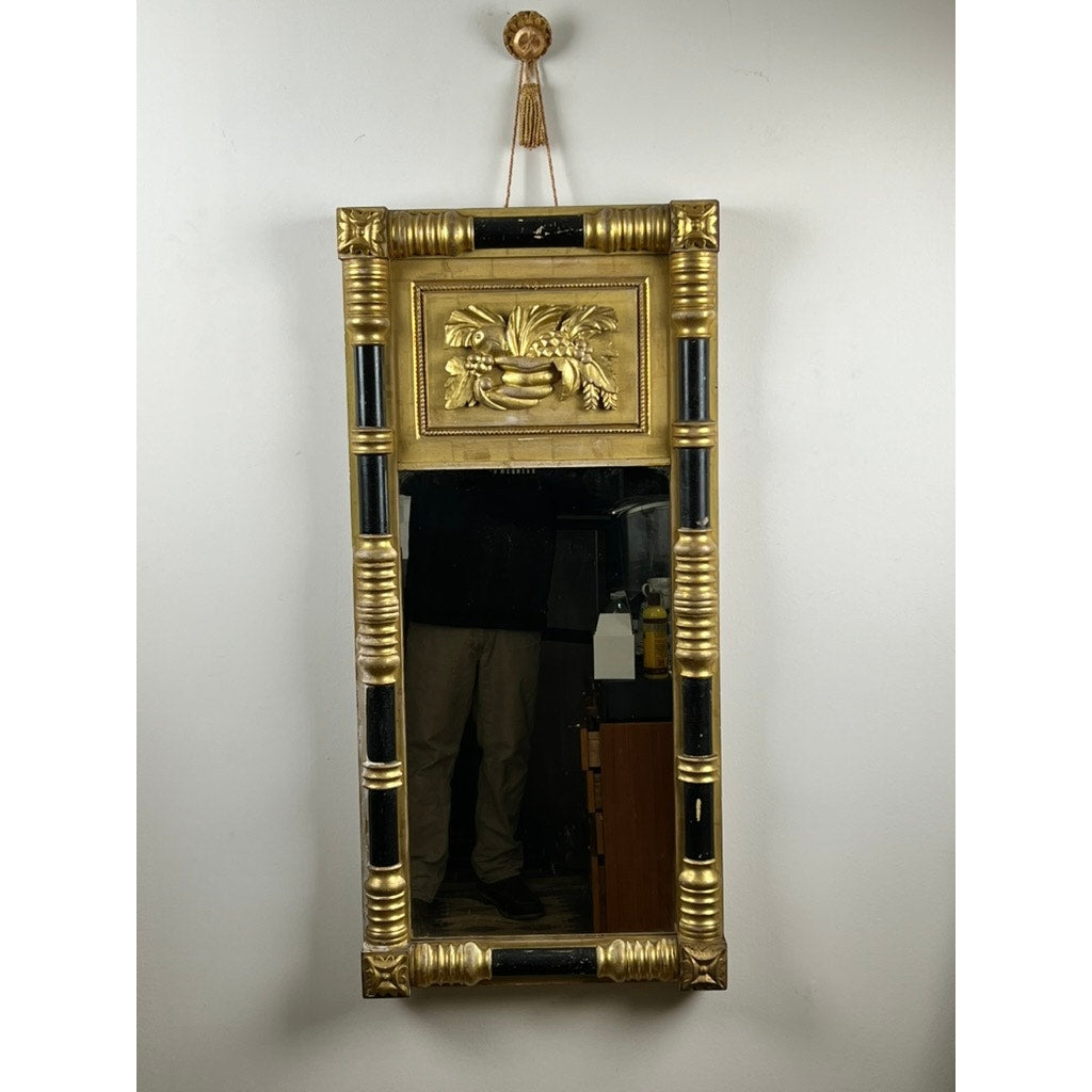Antique Federal Period giltwood mirror c. 1830, features rosette corners and a cornucopia motif; gold and black neoclassical frame. The reflection shows part of a person's lower body. Brand: None/Unknown.