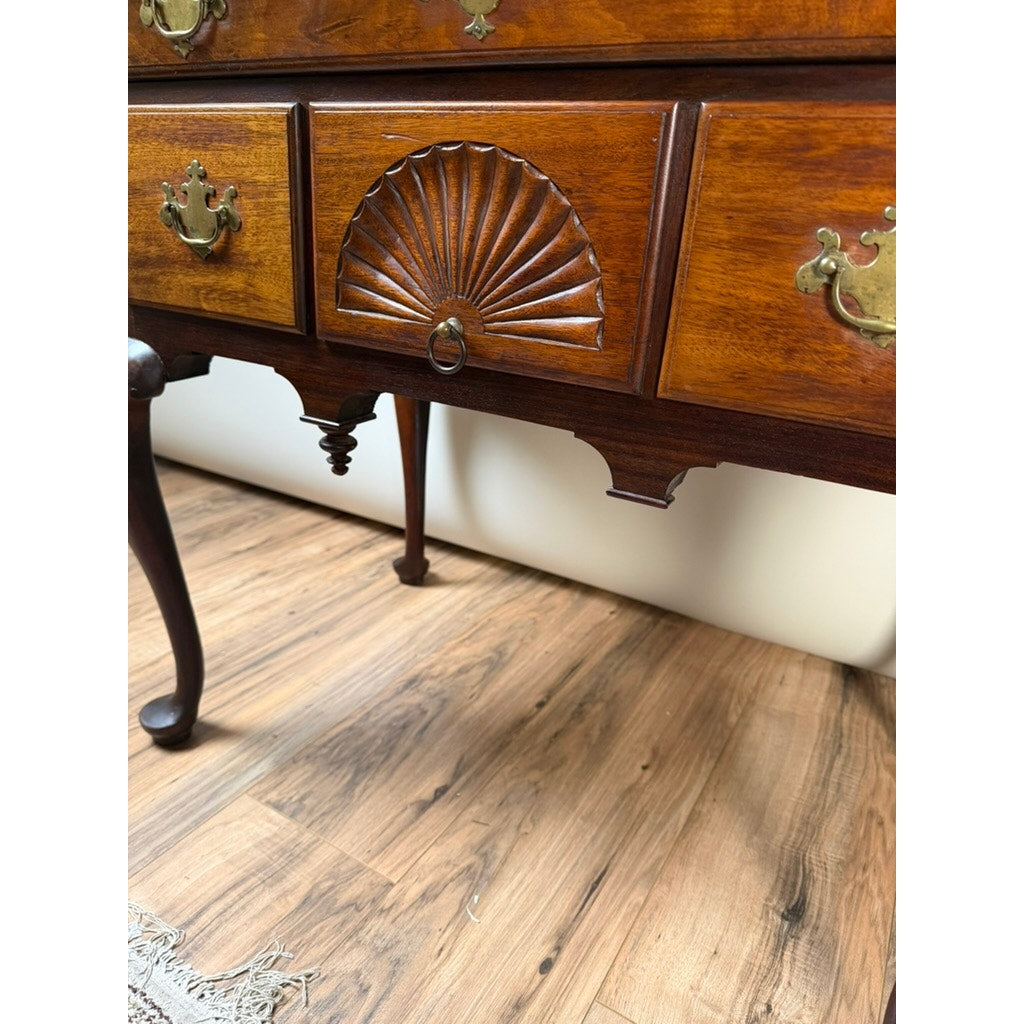 Close-up of an 18th Century American Queen Anne Walnut Shell-Carved Lowboy, c. 1740–1770, featuring brass handles and a carved shell motif on the central drawer, standing on a wood floor.