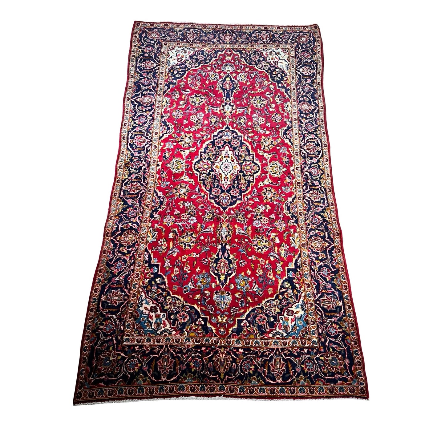 A vintage hand-knotted Persian Kashan wool gallery rug (c. 1950–1970, 4’5 x 8’8) features a rectangular design with a red field, intricate blue, ivory, and gold floral and geometric patterns, and a wide navy border with ornate details.