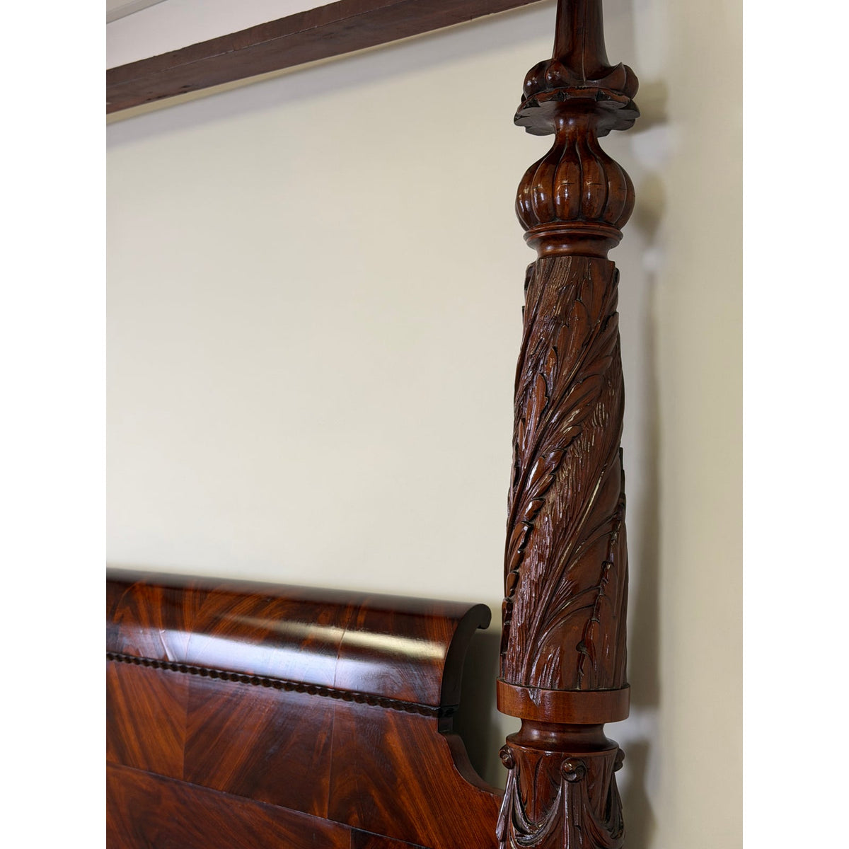 Close-up of an American Classical Carved Mahogany Four-Poster Tester Bed, possibly New York, circa 1825–1840, featuring a 19th-century mahogany vertical post with acanthus leaf detailing next to a curved headboard.