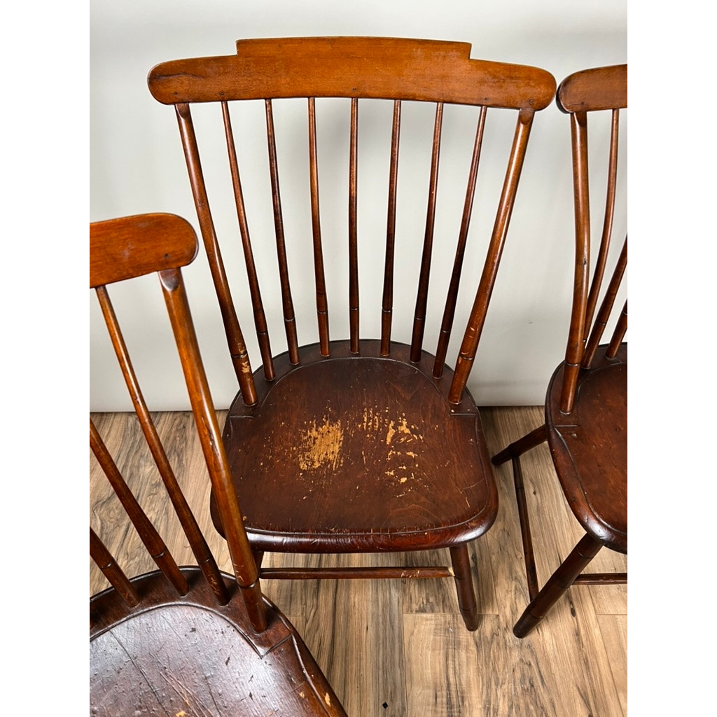 This Antique Set of Four New Hampshire Step Down Windsor Chairs by JR Hunt, c. early 19th century, features curved top rails and vertical slats with visible wear, grouped together on a wooden floor.