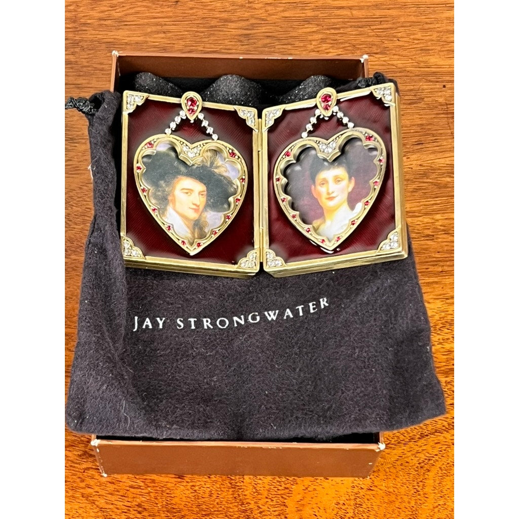 The New in Box Jay Strongwater Bejeweled Enamel Double Heart Picture Frame features jeweled gold hearts and comes in a black pouch. This elegant Jay Strongwater frame makes a stylish accent on any surface.