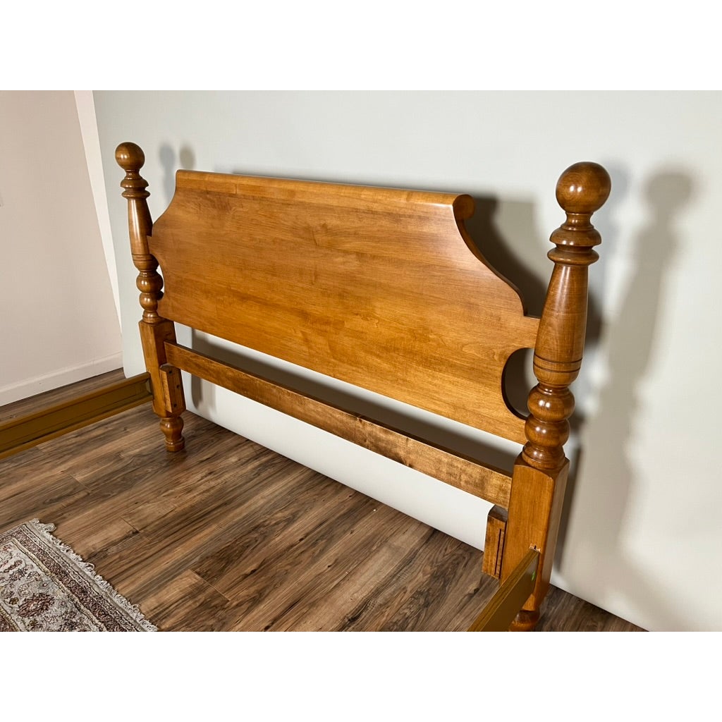 A Vintage Rock Maple Cannonball Queen Size Bed headboard in solid maple with two tall posts topped by round decorative finials.
