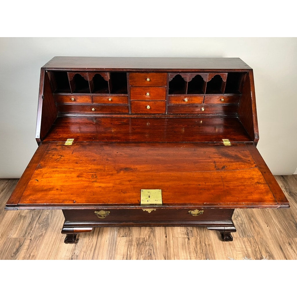 An 18th Century New England Chippendale Cherry Slant Front Desk, Circa 1770–1790, crafted from solid cherry and featuring a fold-down writing surface, multiple small drawers and cubbyholes. This antique piece is adorned with brass hardware and stands on short, carved feet. Brand: None or Unknown.