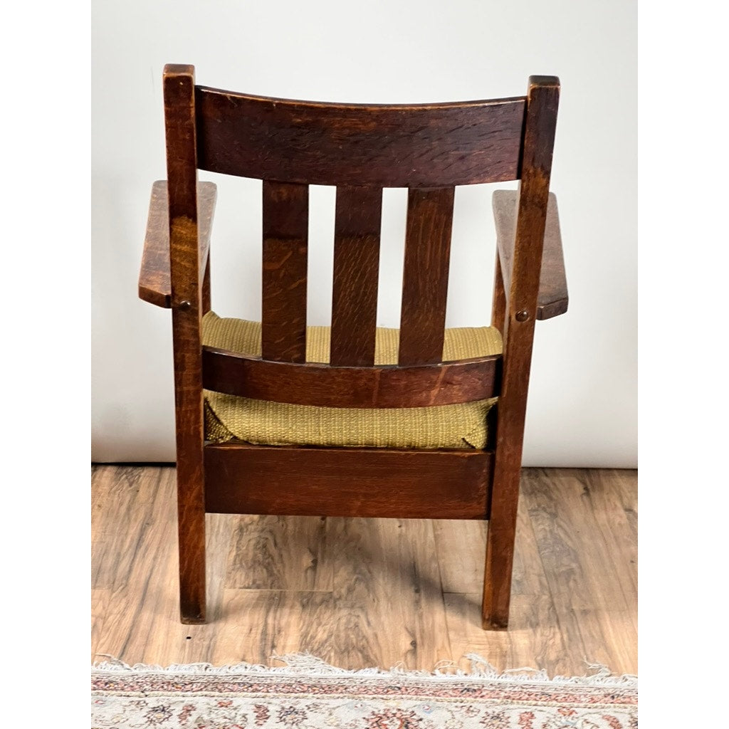 An Antique Quarter Sawn Mission Oak Arm Chair by Quaint Furniture (c. 1920) features vertical slats, a woven seat, and classic Arts & Crafts design—ideal for adding vintage style to any room.
