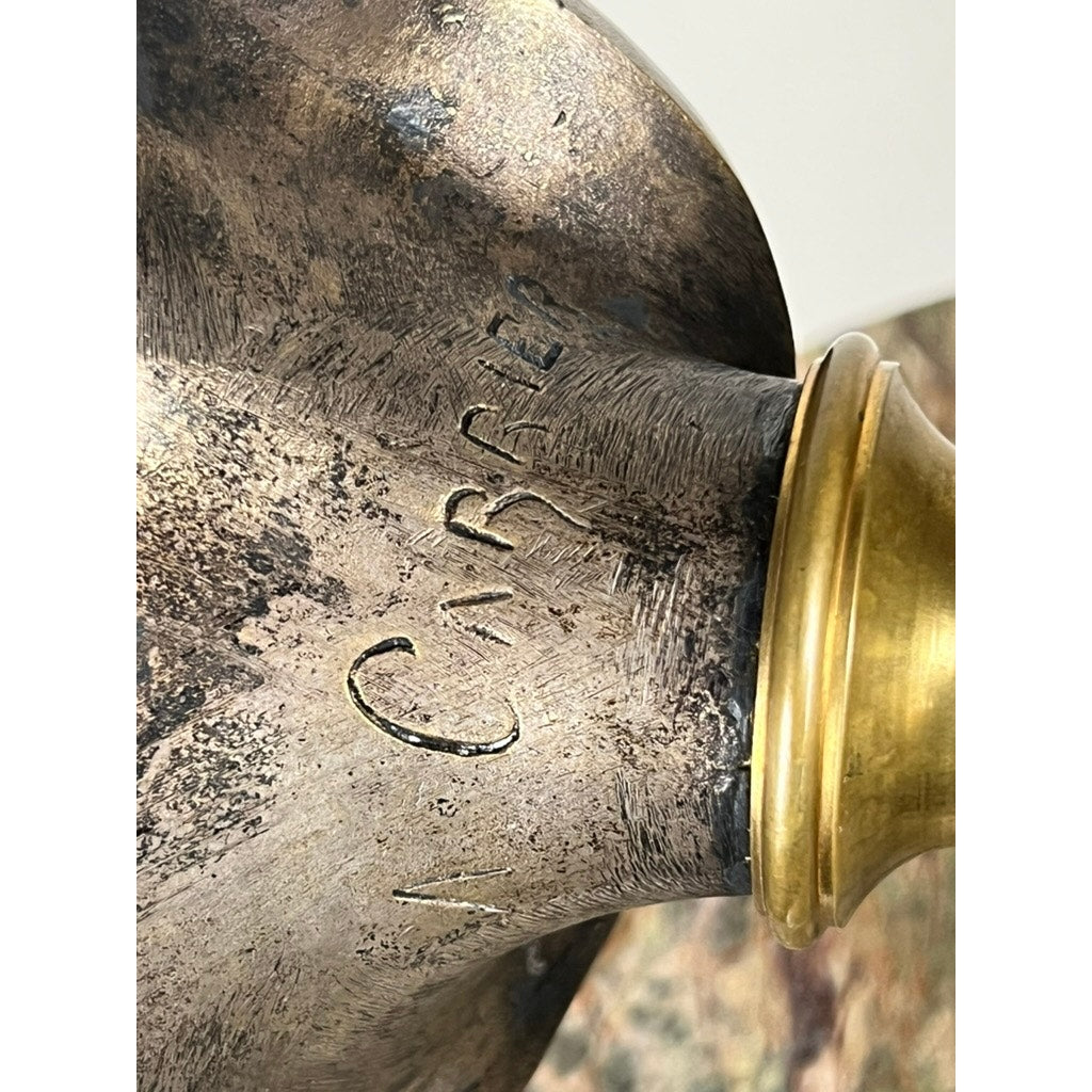 A close-up of a patinated bronze sculpture of Michelangelo by Albert-Ernest Carrier-Belleuse, modeled before 1883 in Paris, showing its weathered gold-colored rim and engraved surface against a blurred, indistinct background.