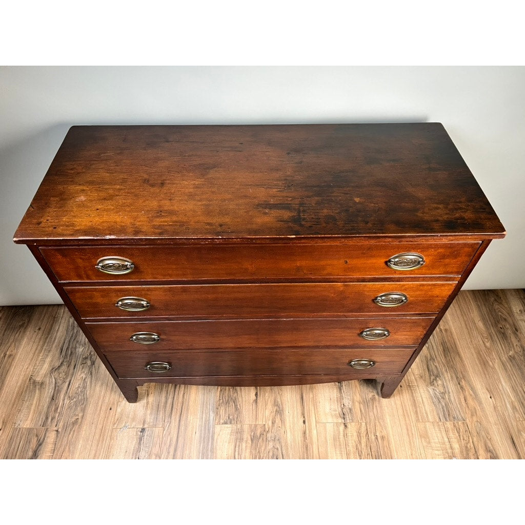 A Rare Labeled William Lloyd Springfield Massachusetts Federal Cherry Chest of Drawers, Circa 1800, featuring four drawers with oval metal pulls, stands on a light wood floor against a white wall. The cherry surface displays gentle wear and patina characteristic of early American craftsmanship.